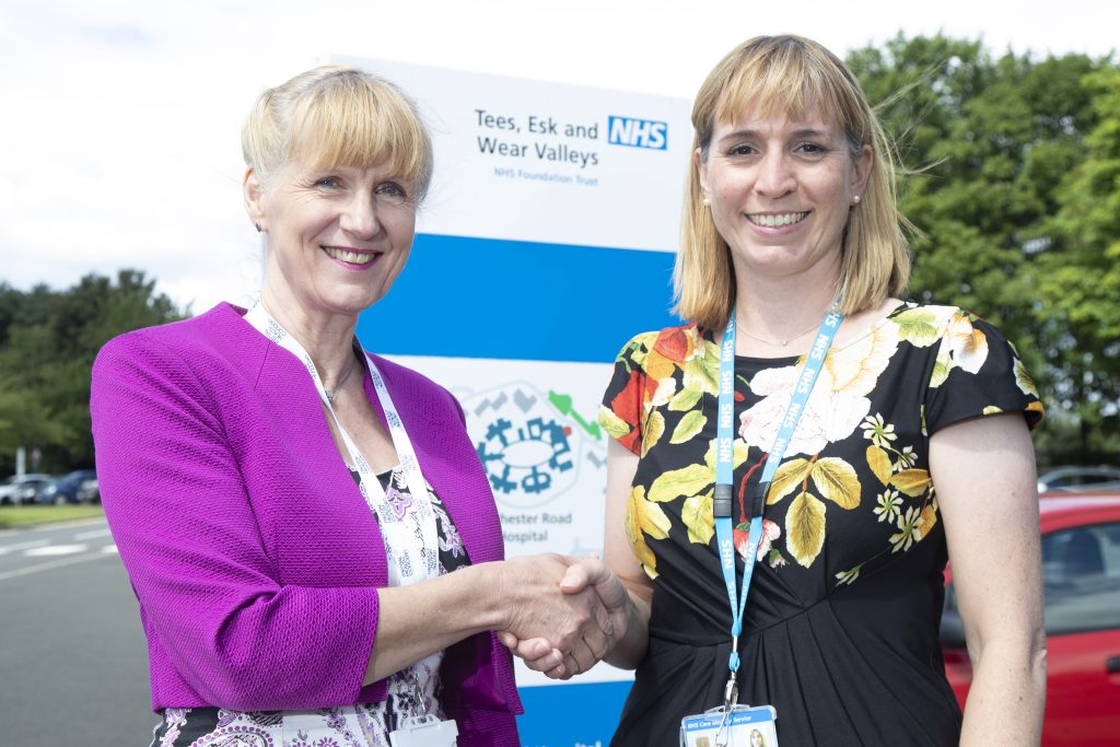 Julia Perry, Head of Community and Wellbeing Services, at Mental Health Concern shakes hands with Rachel Smith, a consultant applied psychologist with TEWV.