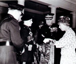 This photo was taken in 1961, when Bob was a Junior Pipe Major and presented to Royalty. Pictured left to right are: Lt Col LHM Gregory, Bob Etherton with his pipes, Major General L de M Thullier and the then Princess Royal. (Princess Mary – the aunt of Queen Elizabeth II).