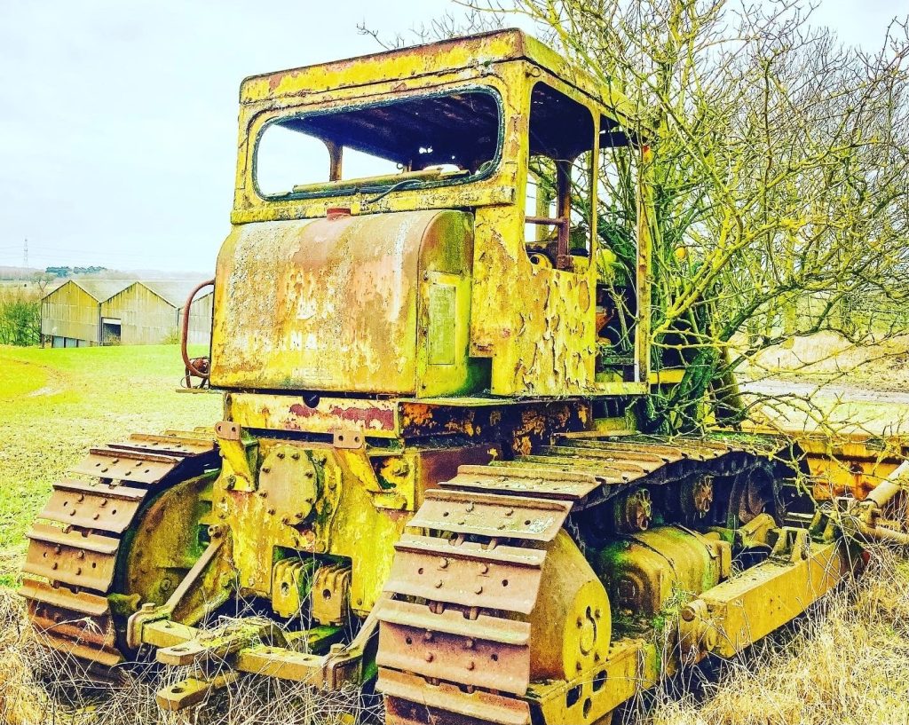 A piece of farm equipment with weeds growing out of it - finding beauty in the everyday.