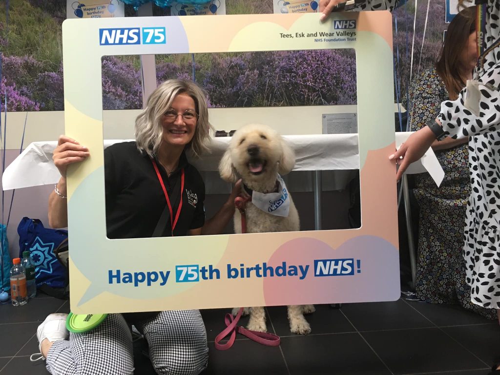Staff and a dog having a picture for NHS75 as featured in our summer 2023 carer newsletter