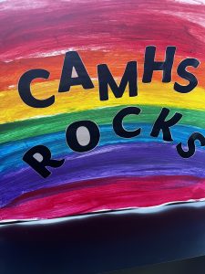 A sign with a rainbow and the text CAMHS rocks.