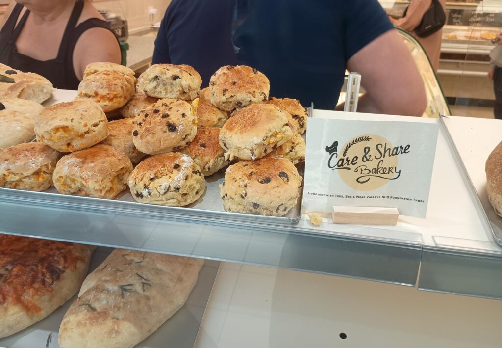 Scones in the bakery window with the Care & Share label and logo.