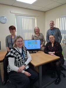 CAMHS colleagues around a table with a PC showing the CAMHS homepage