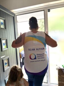 Sarah showing the back of her GNR running top - which reads "Team Autism"