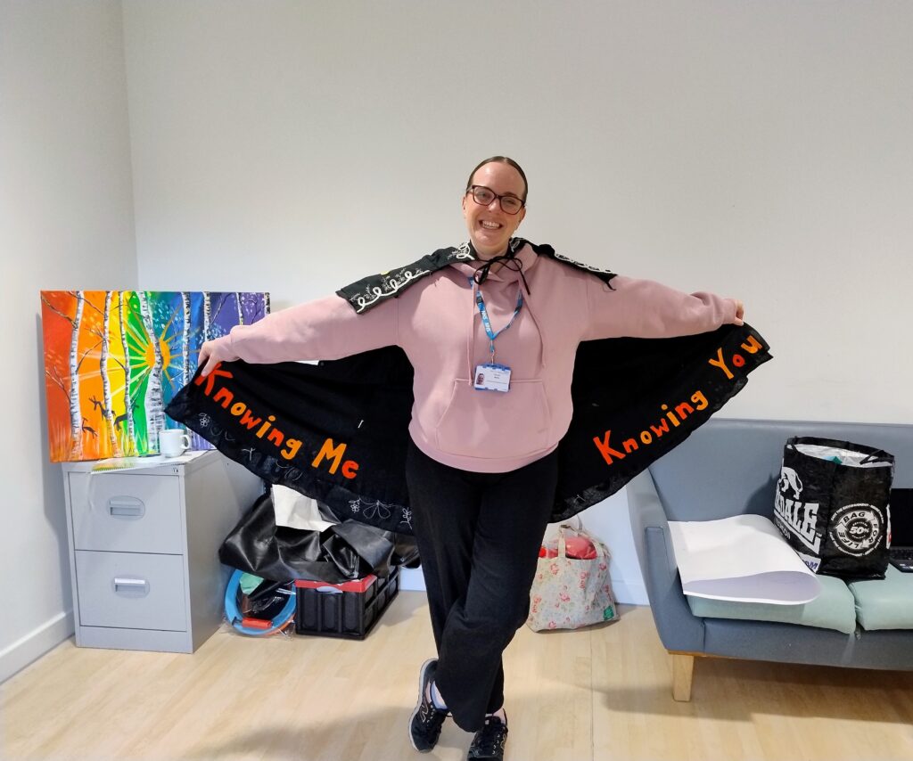 A photo of occupational therapist Devon Wells smiling whilst wearing the 'Cape of Good Health'