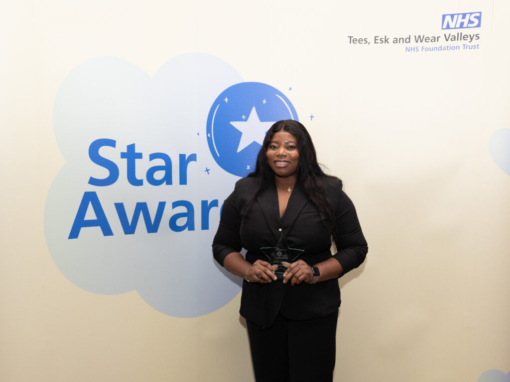 Living our values winner Sidikat sanding in front of star awards banner.