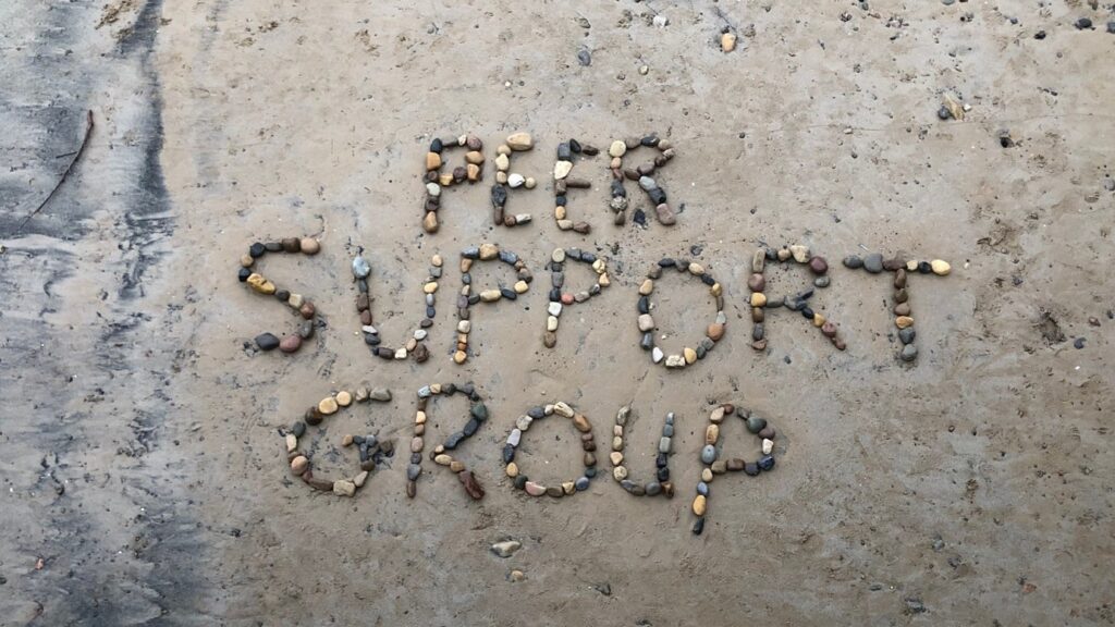 Rocks on a beach saying: "peer support group"