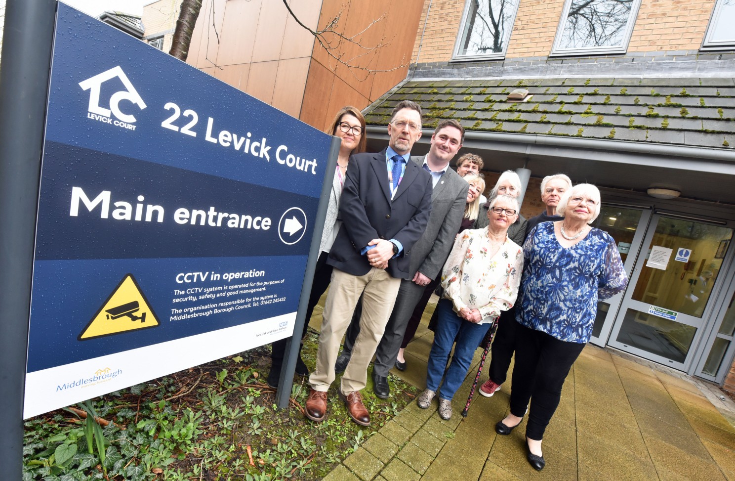 Representatives from organisations and family members stand outside Levick Court.