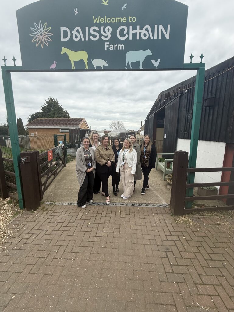 Trust and Daisy Chain staff under the main entrance sign go Daisy Chain