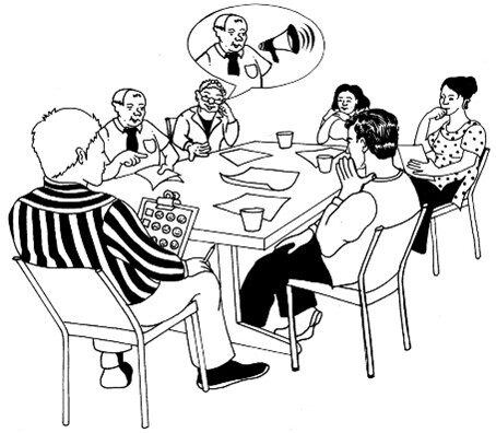 A group of 6 people sat around a table having a conversation.