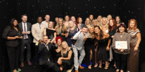 All our Star Awards winners gathered together with their trophies with a black curtain behind them with twinkling lights.