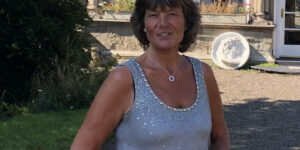 Andrea smiling, standing in front of a building